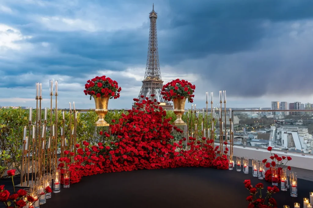 Exclusive Eiffel Tower view event setup at Shangri-La Paris featuring abundant red roses, floating candles, and luxury décor elements by Kiss Me in Paris production team