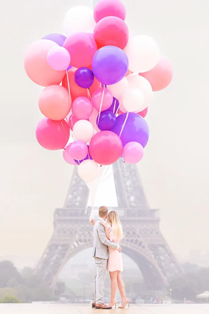 Happy couple celebrating Paris proposal at Trocadéro with colorful balloon bouquet and Eiffel Tower backdrop during romantic rainy day engagement photoshoot